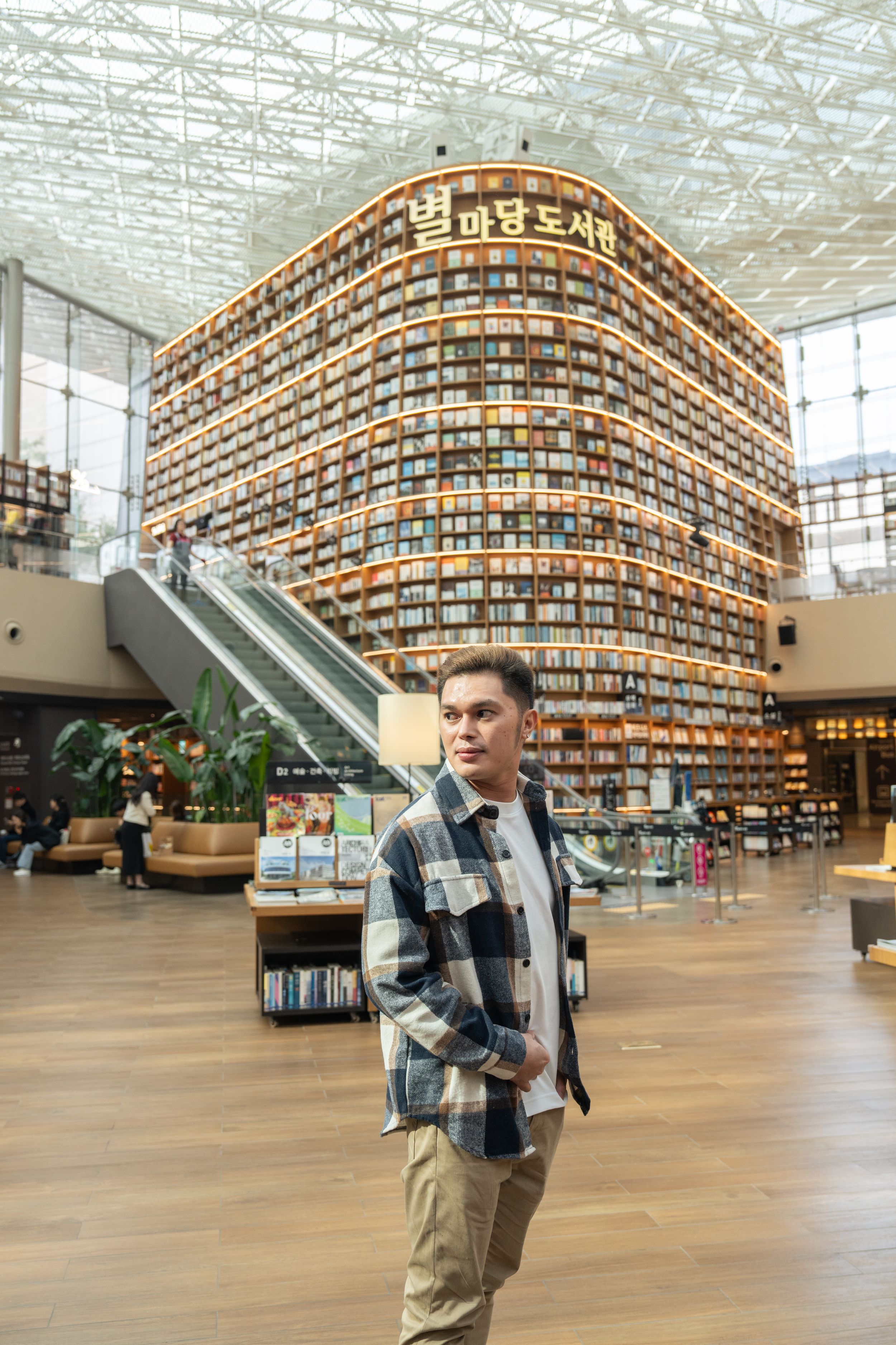 A person exploring a spacious modern library with curved wooden bookshelves and natural lighting.