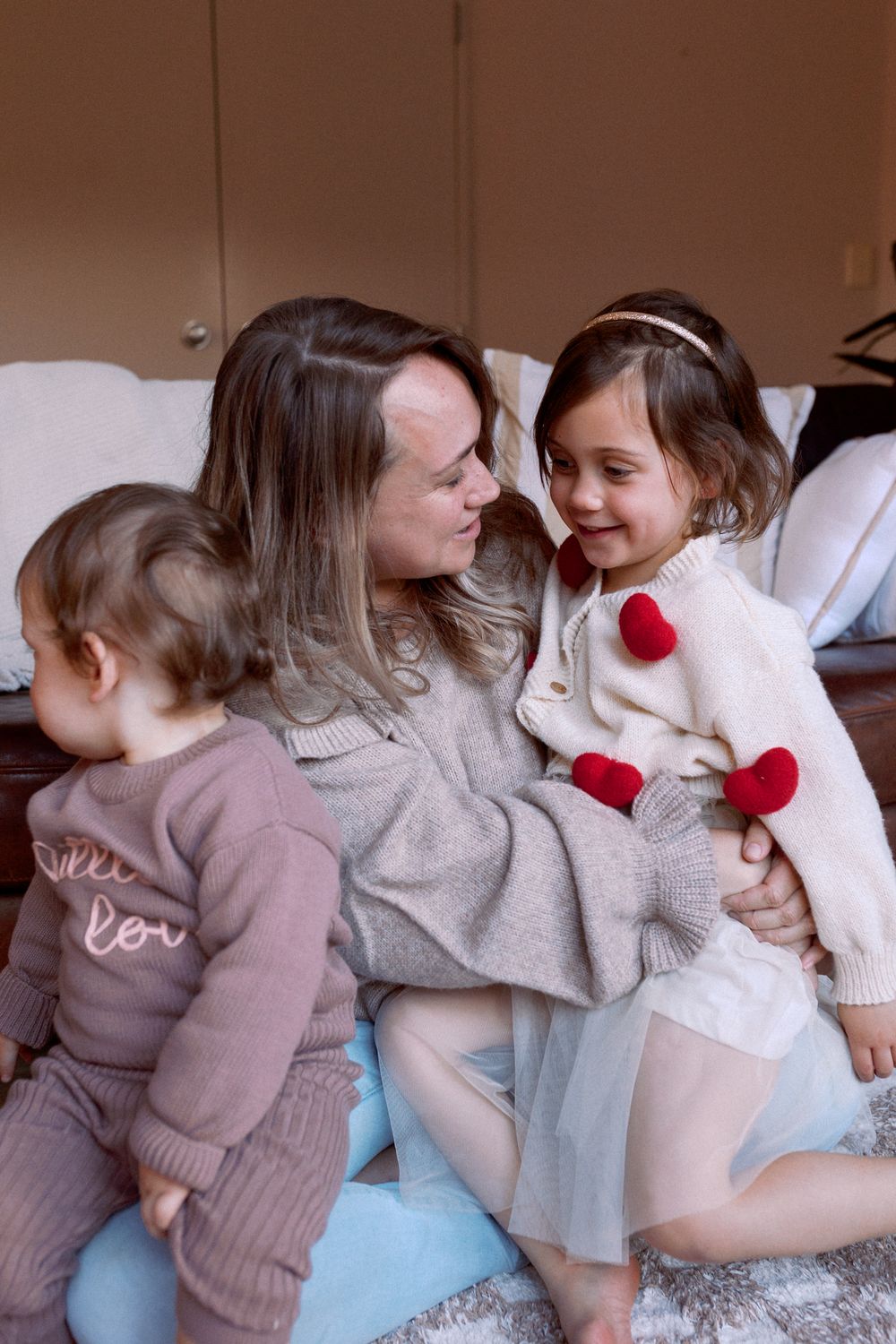 People in cozy sweaters sharing a tender moment together on a light blue surface.