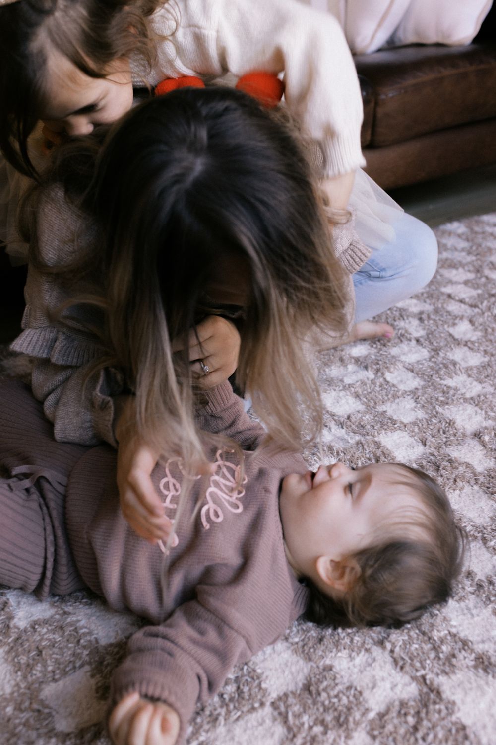 Intimate family playtime captured in a sequence on a patterned carpet.