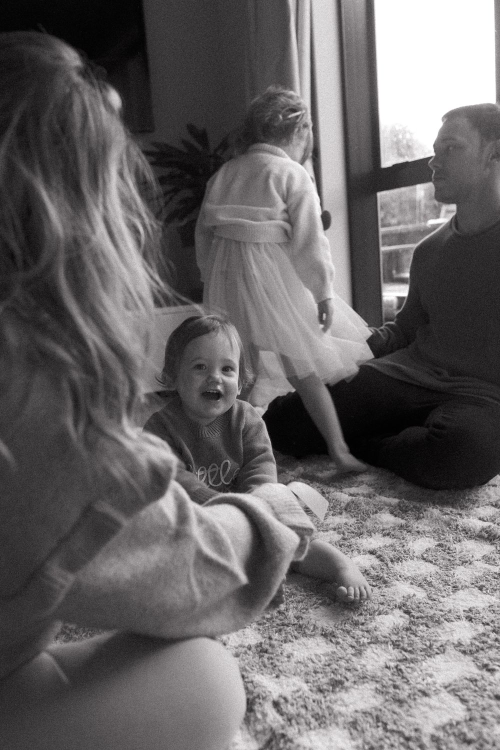Black and white photo of playful moments on a textured carpet.