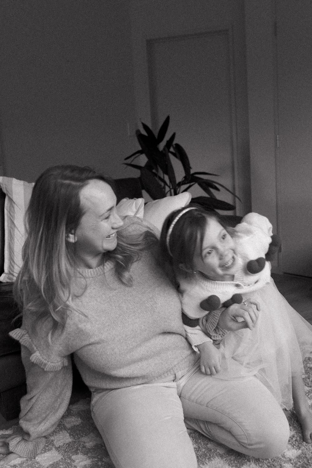 Candid black and white images showing loving family interactions on a bed.