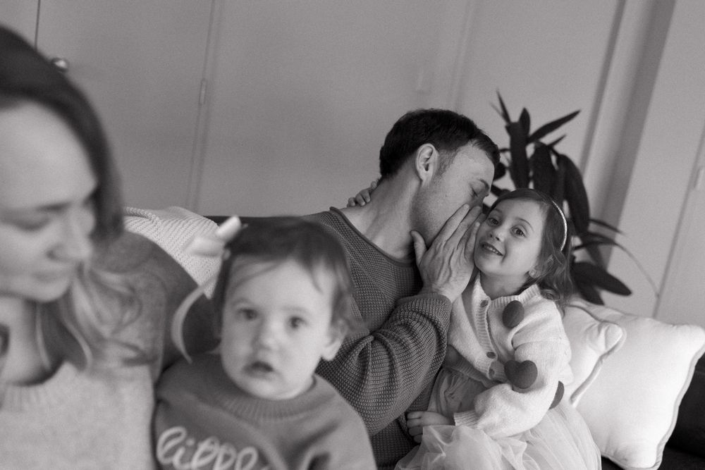 A sweet moment of play and interaction between a toddler and adults on a couch.