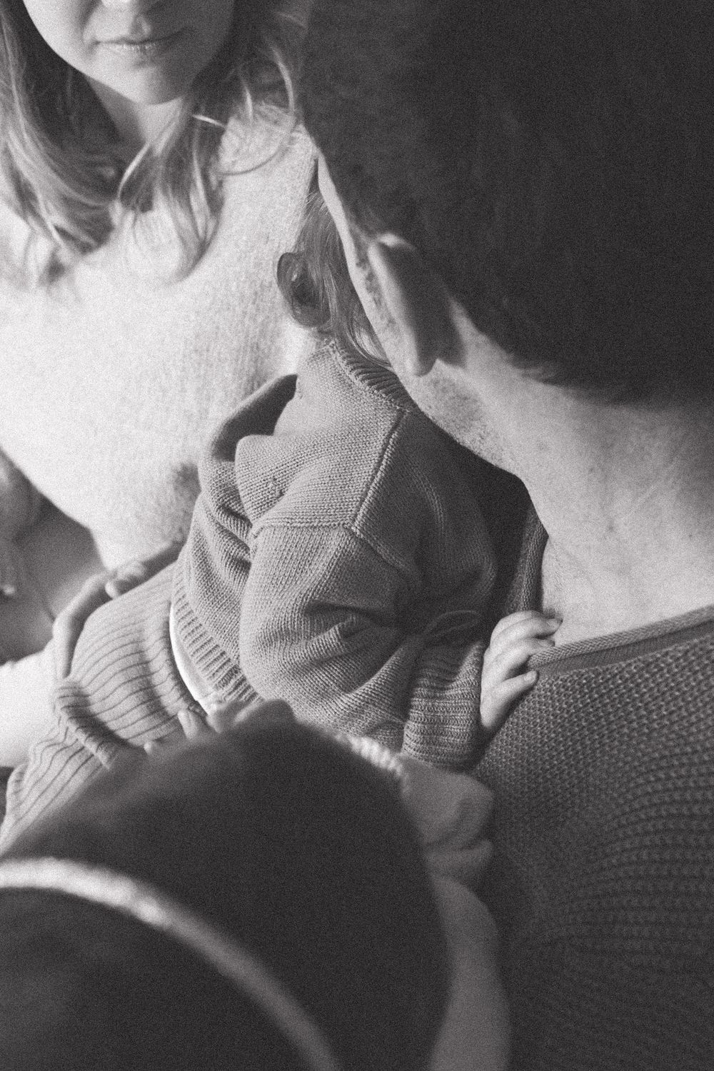 Black and white close-up of people in sweaters embracing.