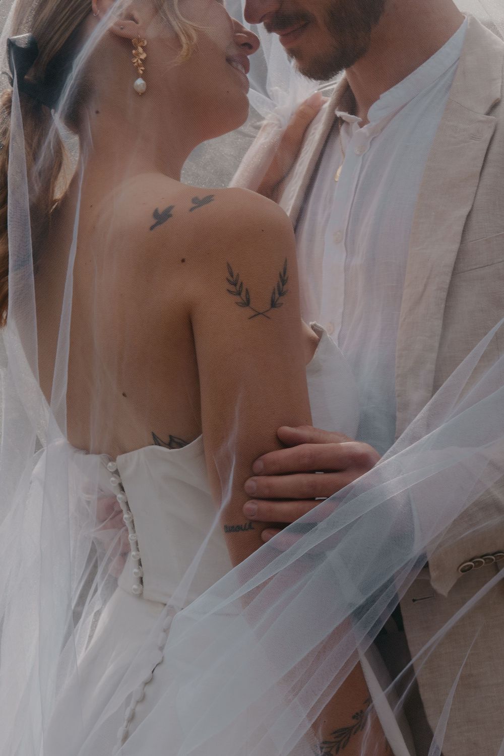 A couple in wedding attire with flowing veil and delicate details.