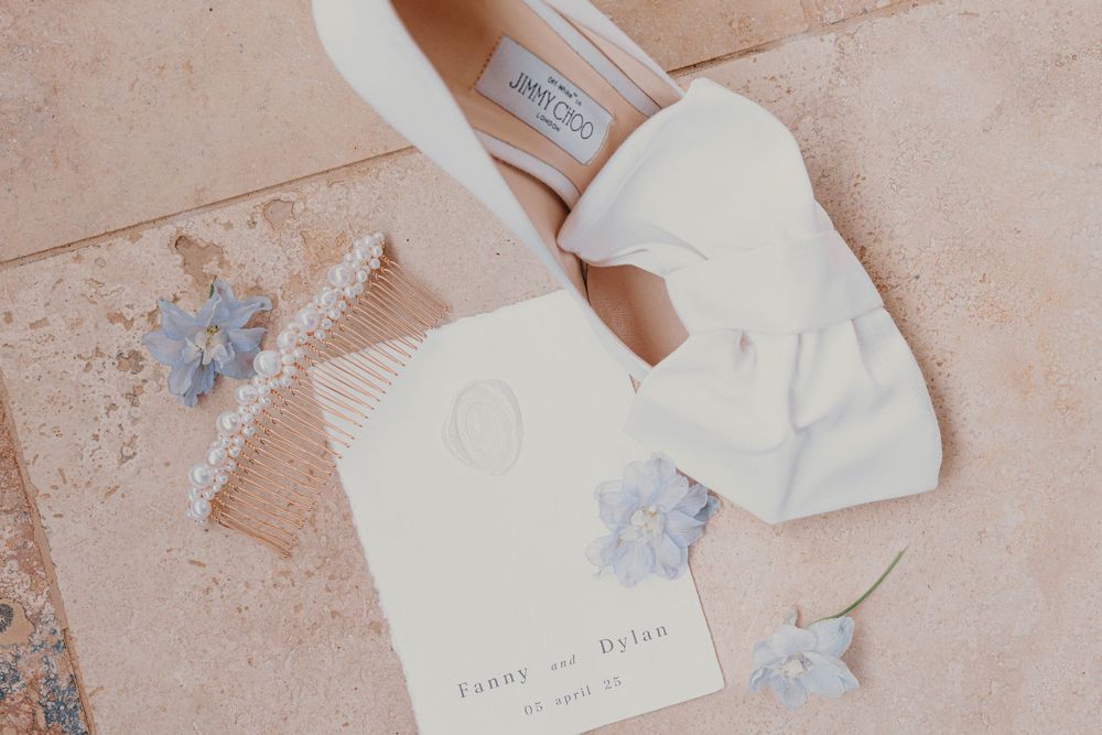 Delicate wedding stationery with white and blue details on a blush pink background.