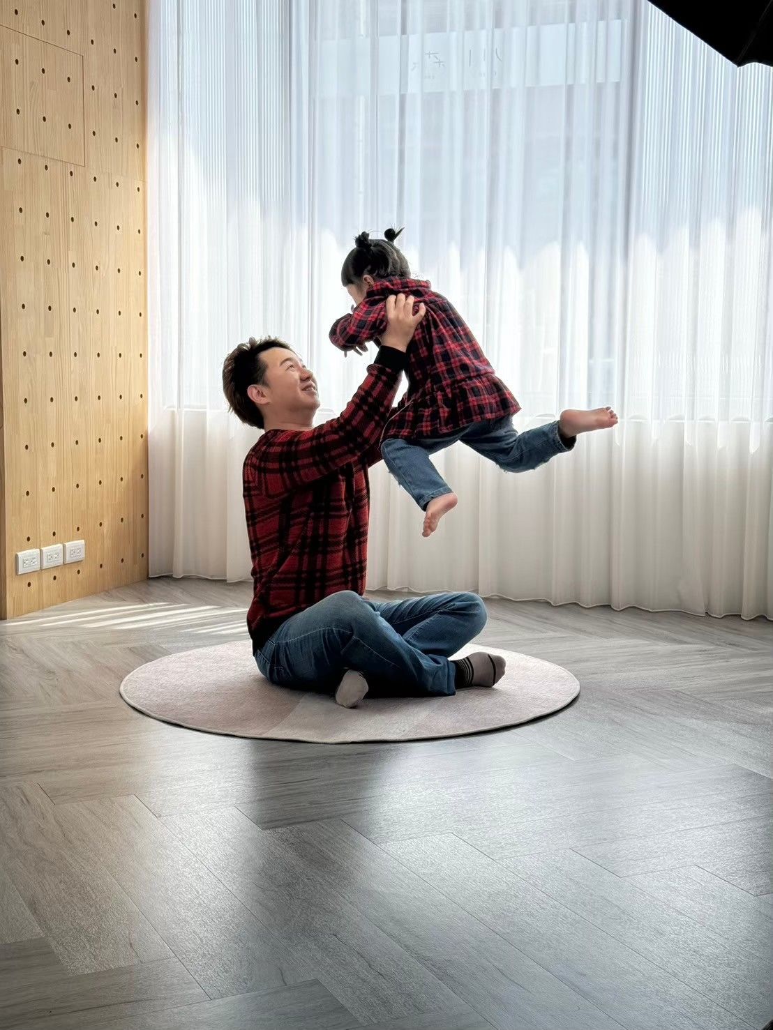 A person in a plaid shirt demonstrates a rolling motion sequence on a circular platform indoors.