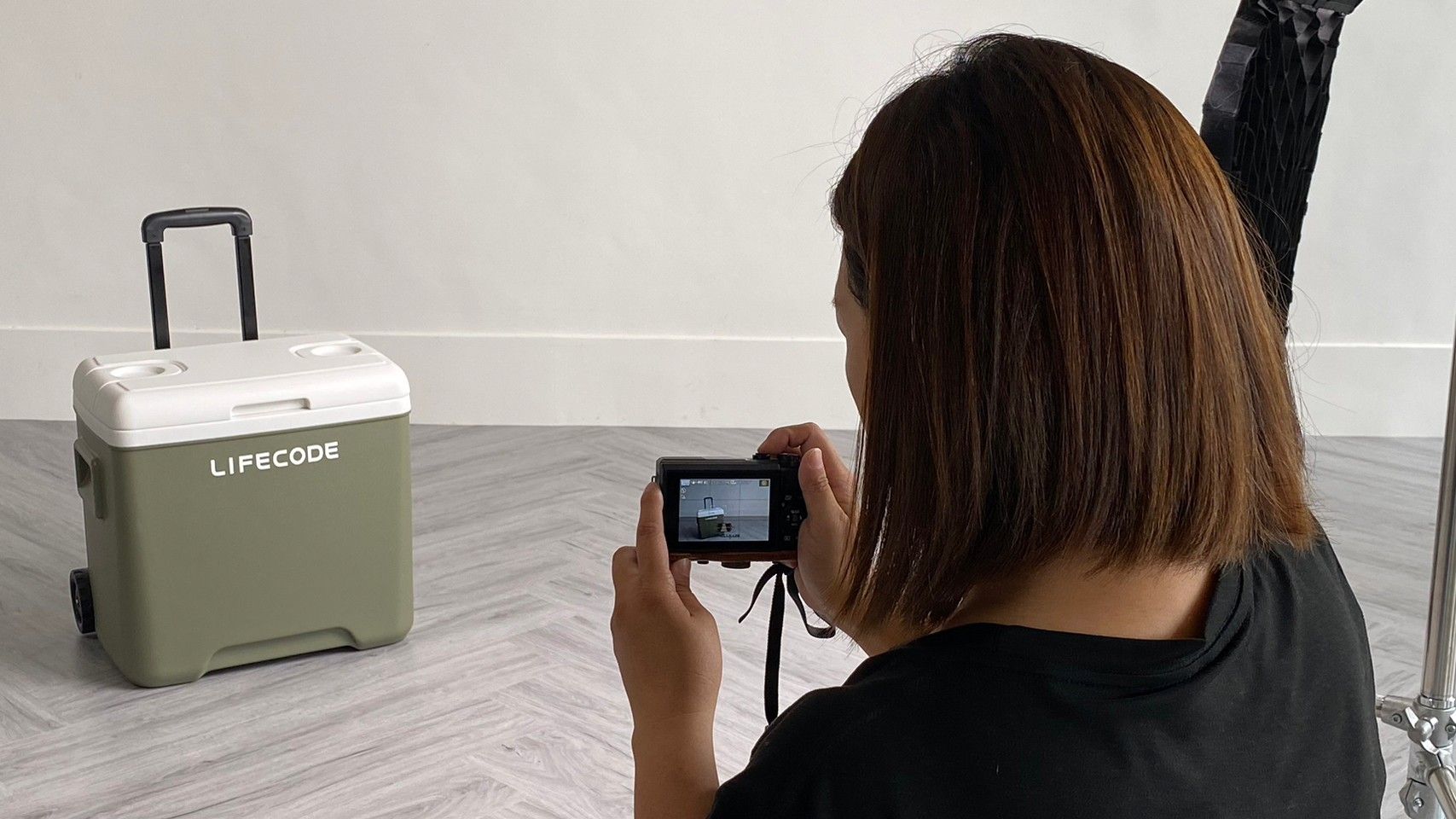 Behind-the-scenes photo shoot setup with lighting equipment and green screen in a modern minimalist space.