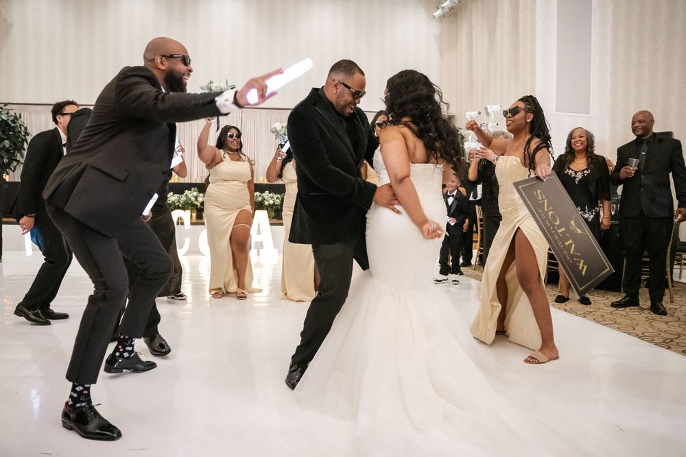 Wedding party poses for a creative action shot leaping and dancing in a bright white venue.