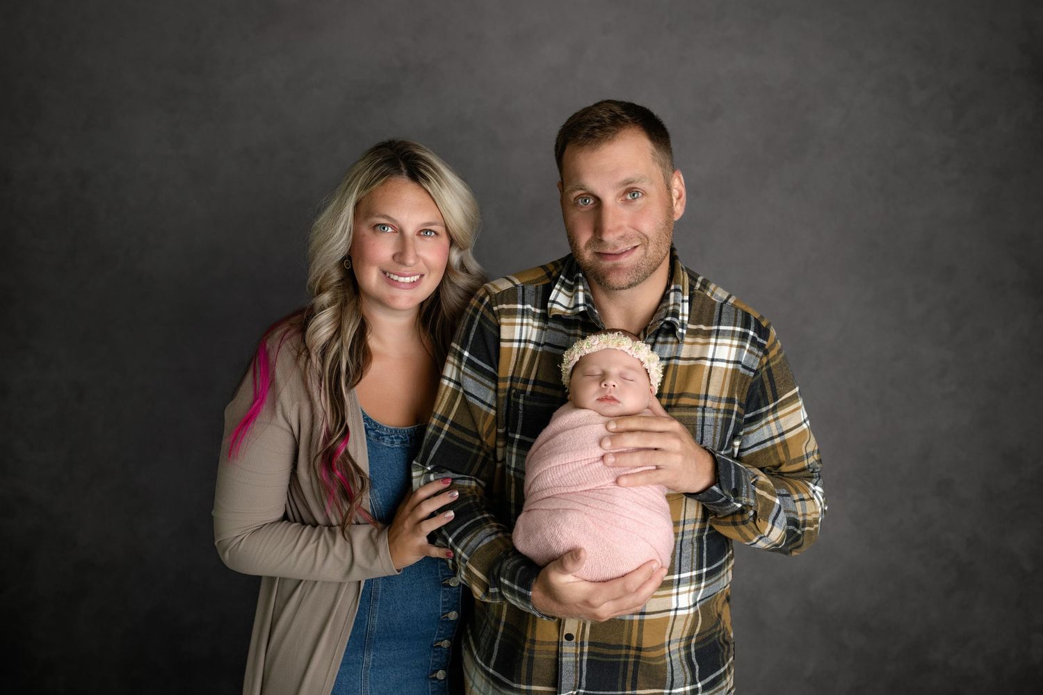 Couple sharing intimate moments while holding something small and pink against dark studio background.