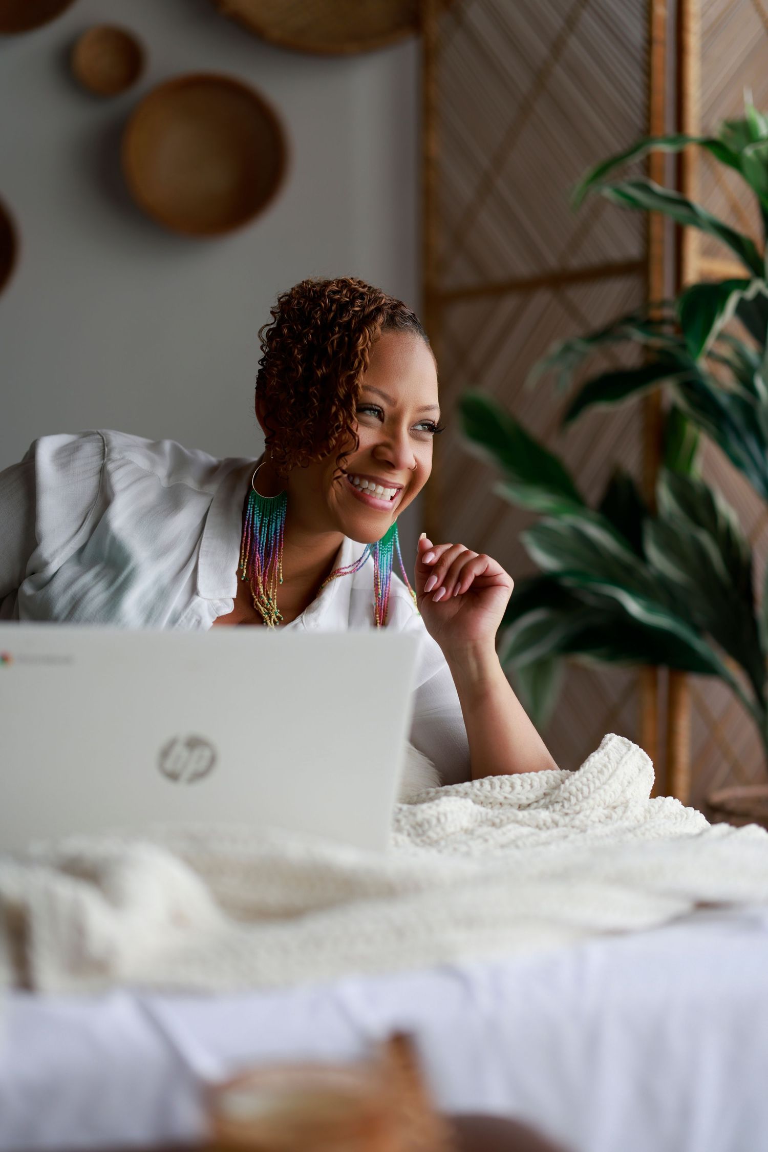 Person lying on white bedding in cozy setting with indoor plants visible in background.