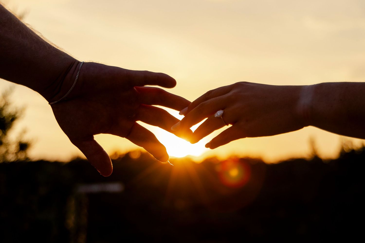 Creative silhouette engagement photo of two hands reaching for eachother in the sunset in Dripping Springs Texas.