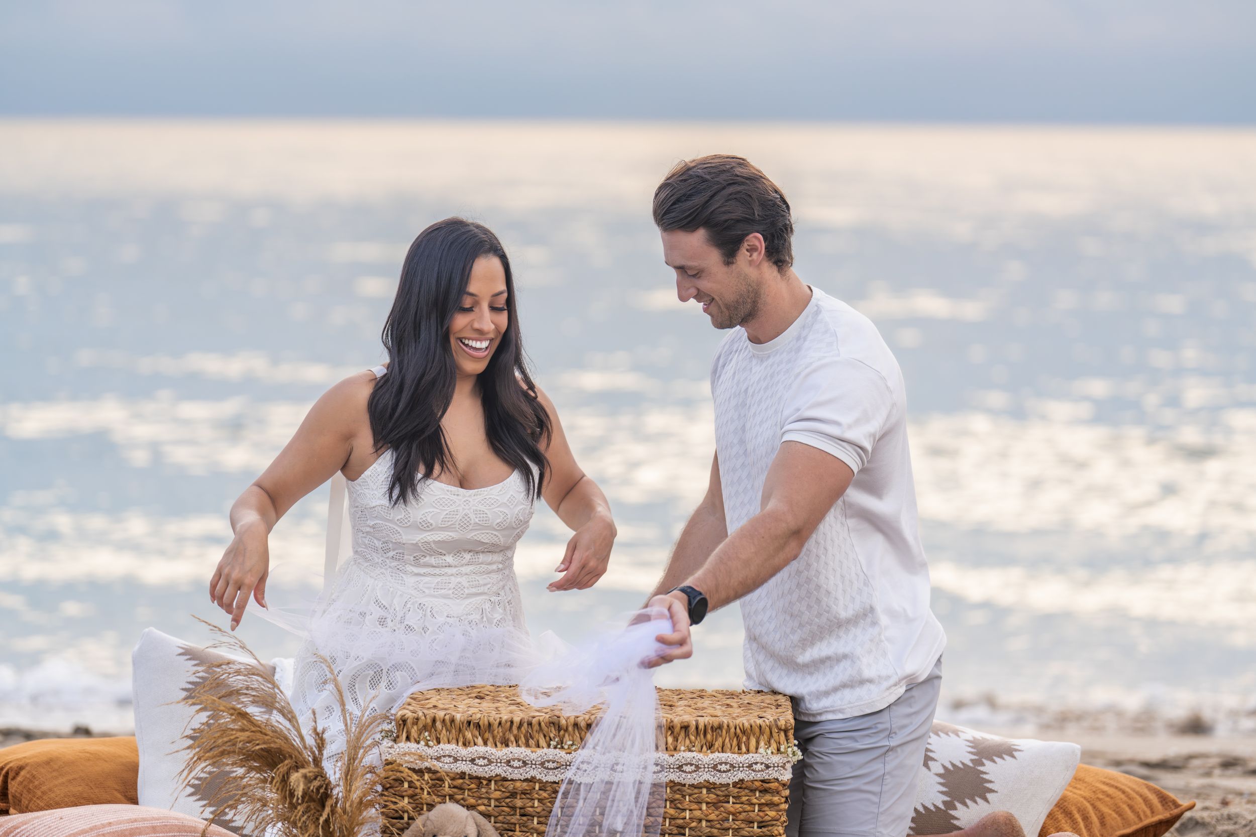Couple enjoying intimate picnic moment on sandy beach at golden hour.