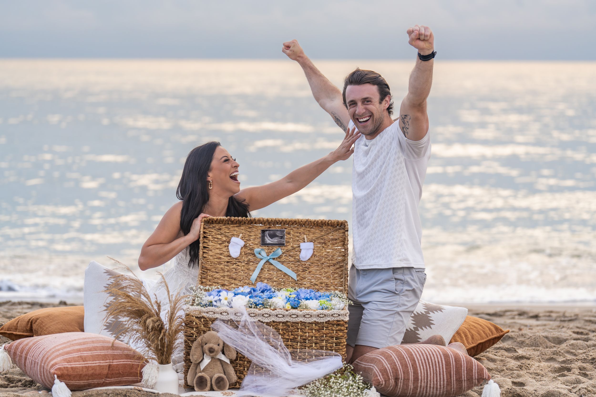 Joyful celebration on beach with couple sharing special moment near picnic setup.