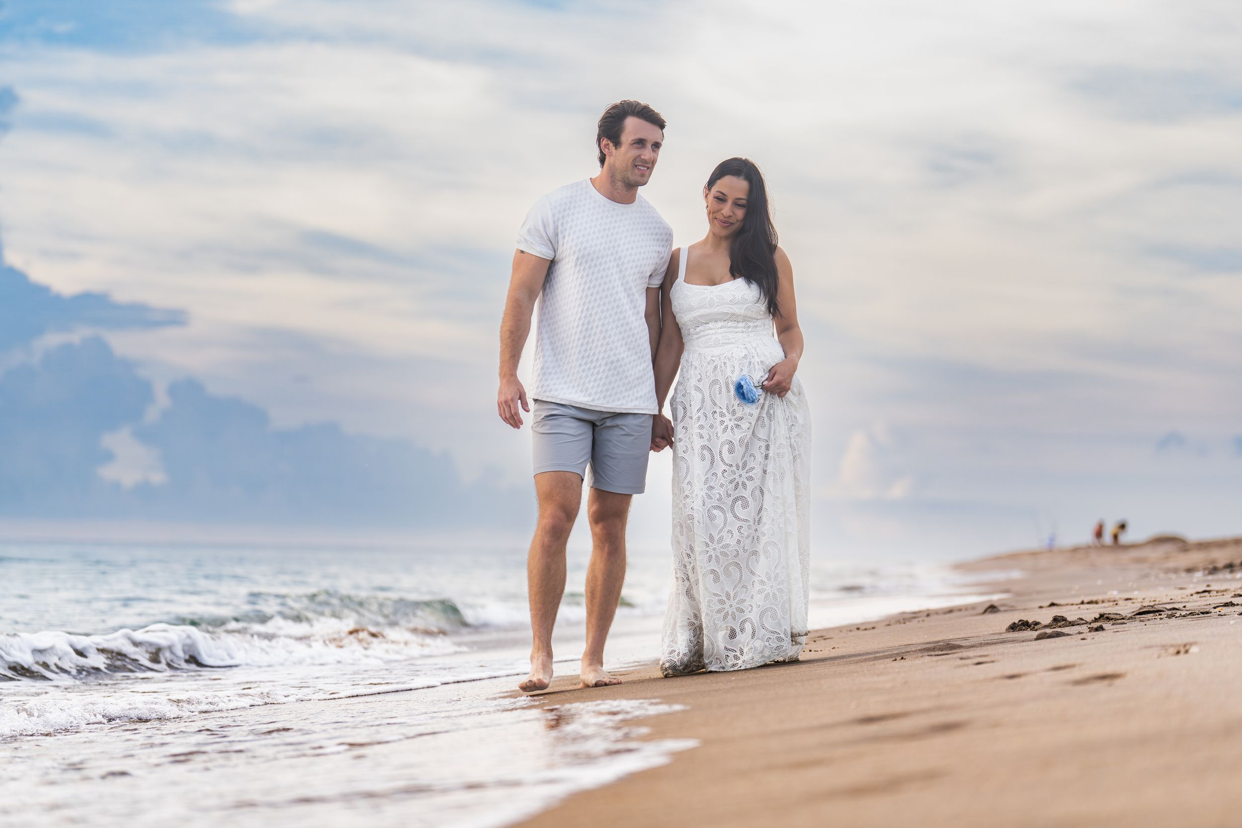 Happy couple enjoying romantic beach walk together near crashing waves at sunset.
