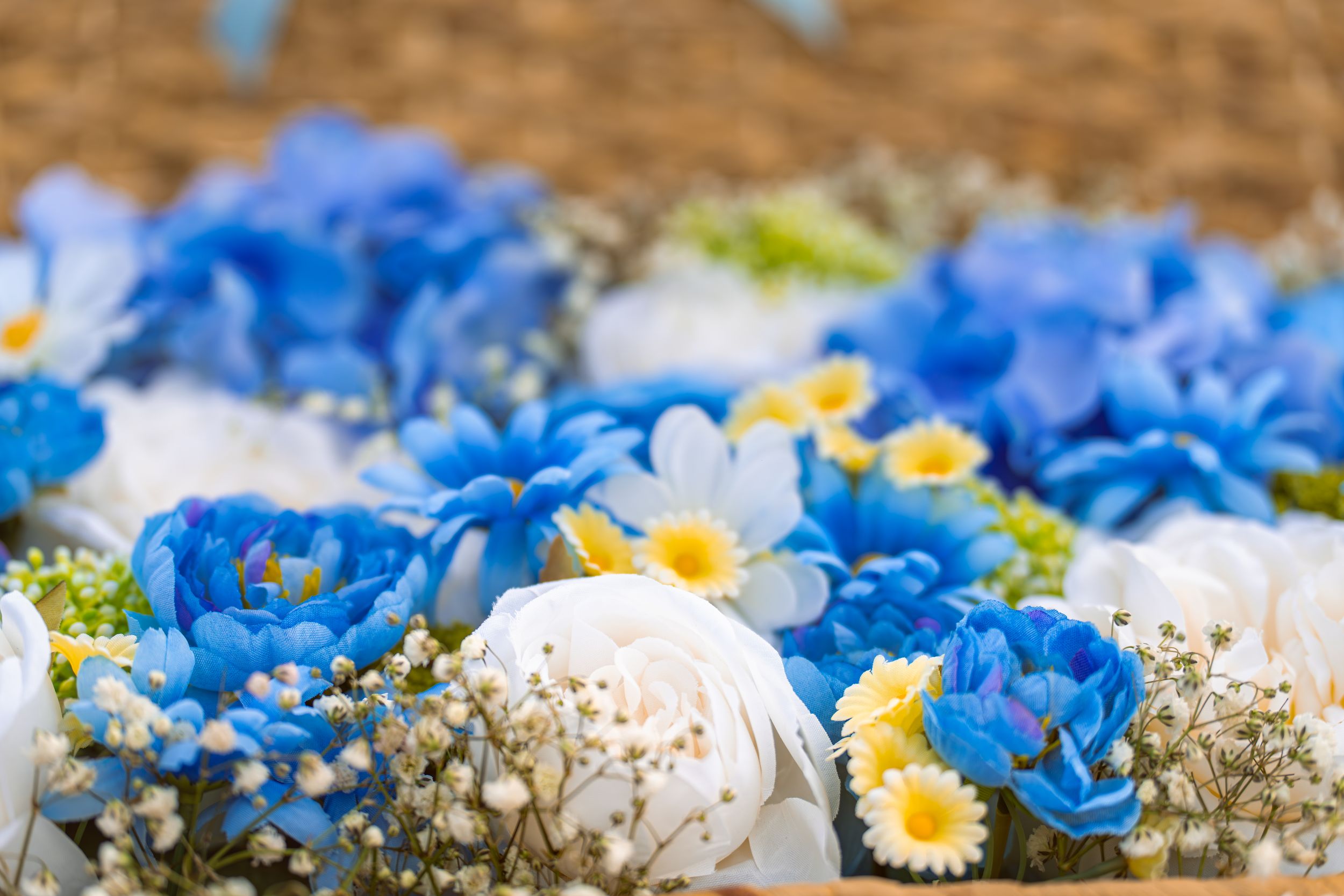 Beautiful arrangement of blue roses with daisies and baby's breath flowers on golden surface.