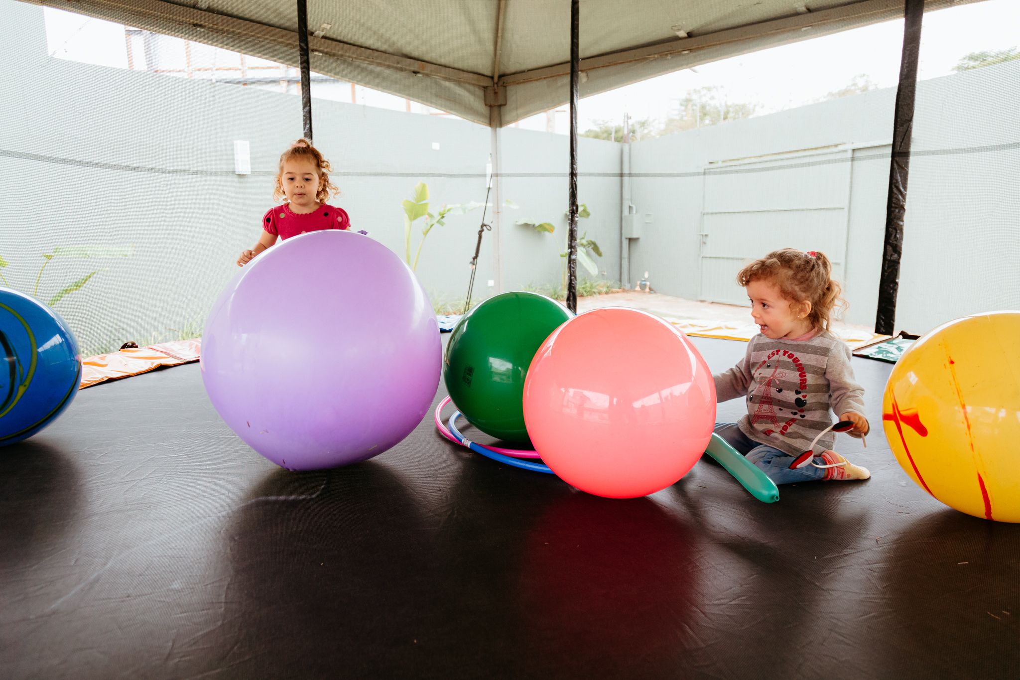 A sequence of vibrant, colorful balloons being deflated and popped one by one in an indoor setting.