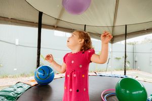 Children play with colorful balloons during indoor activity with balloon tapping and bouncing exercises in a covered space.
