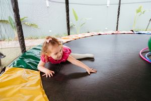 Children playing with colorful plush toys and exercise equipment in an indoor activity space.