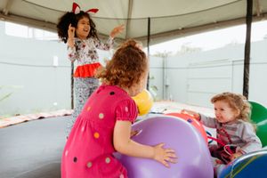 A child plays with colorful balloons in a white tent at an outdoor party or event.