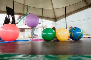 Colorful oversized balloons arranged under a white canopy tent create a festive outdoor display.