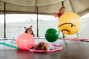 Colorful inflatable pool toys and floats laid out on a covered patio area with filtered sunlight coming through.