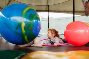 Team members roll across an exercise floor with large colorful stability balls during a group fitness activity.