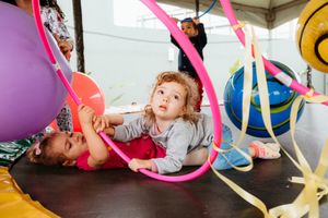 Children playing and having fun with colorful ribbons and balloons during an engaging indoor activity.