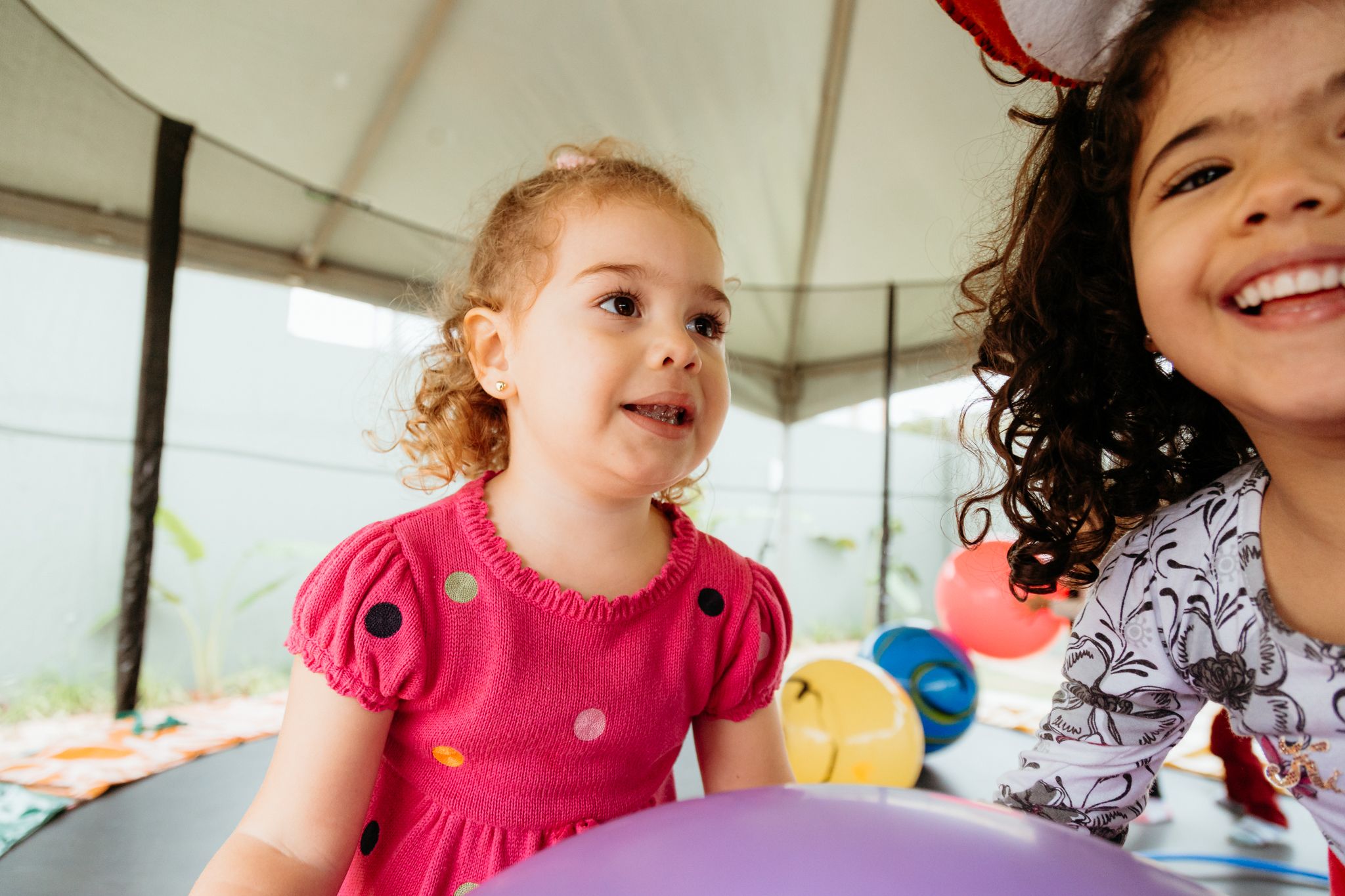 Young children playing with balloons during a fun indoor party celebration.