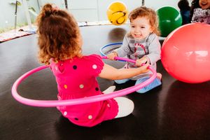 Children playing with colorful balloons and toys during activities session with curved line showing sequence of moments.