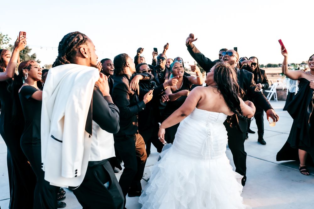 Wedding guests dance and celebrate joyfully at an outdoor reception party.