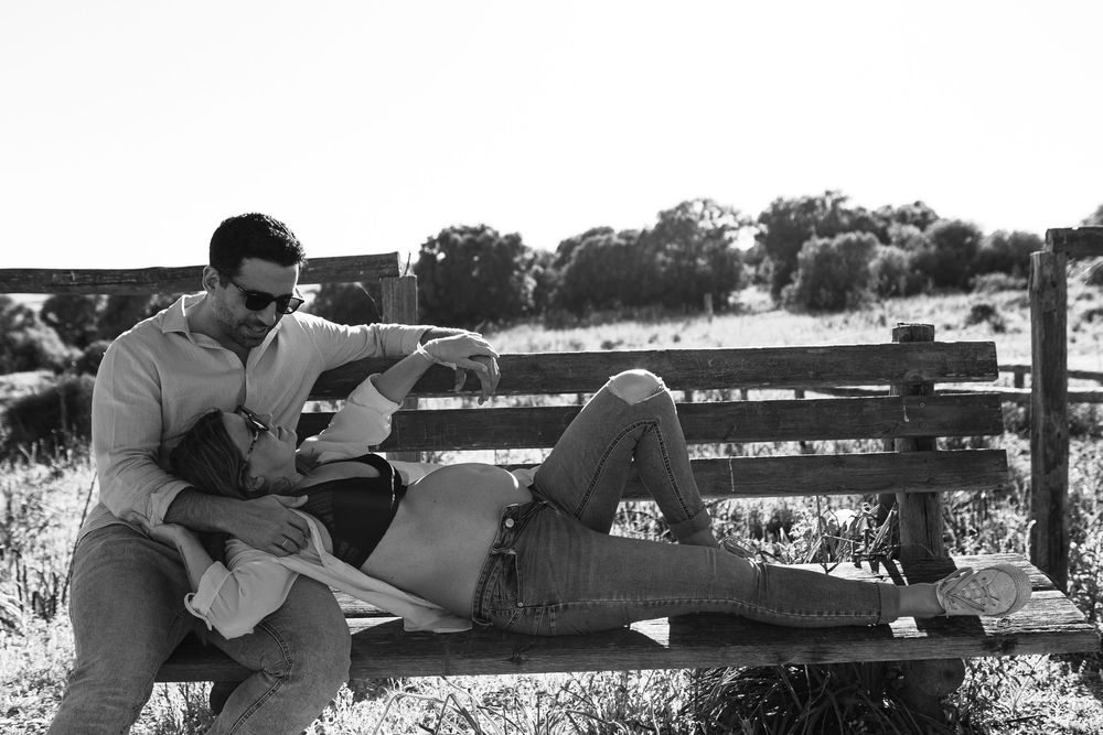 A romantic black and white photo series shows a couple embracing and kissing on a park bench.