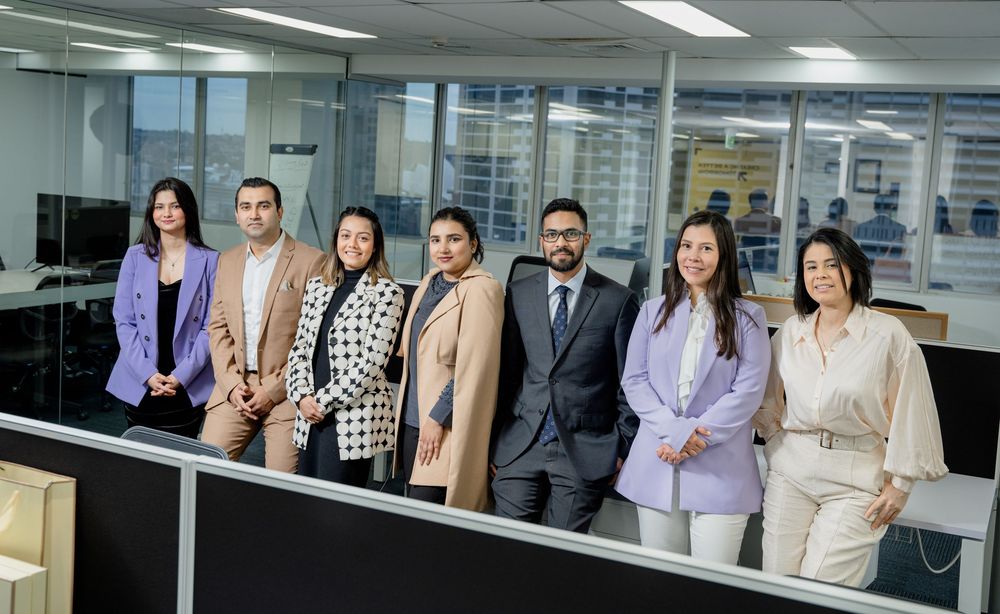 Professional group of business people standing together in a modern corporate office corridor.