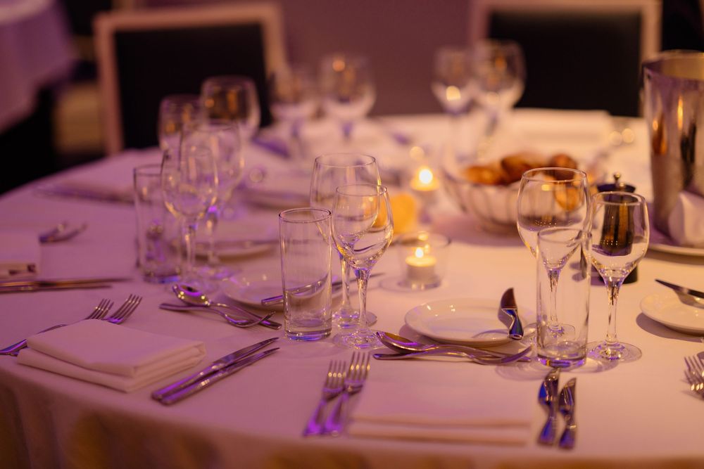 Elegant table settings with white linens and wine glasses arranged for a formal dining event.