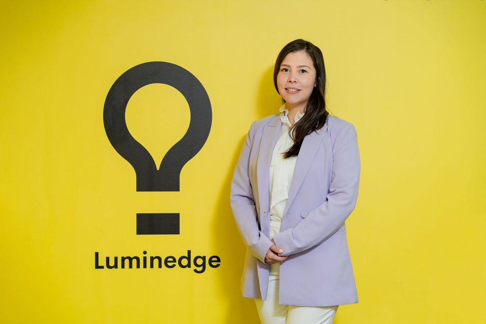 Professional standing in front of yellow wall with Luminedge company logo.