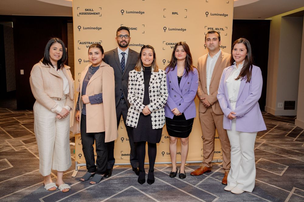 A group of people in formal attire pose together at a corporate networking event.