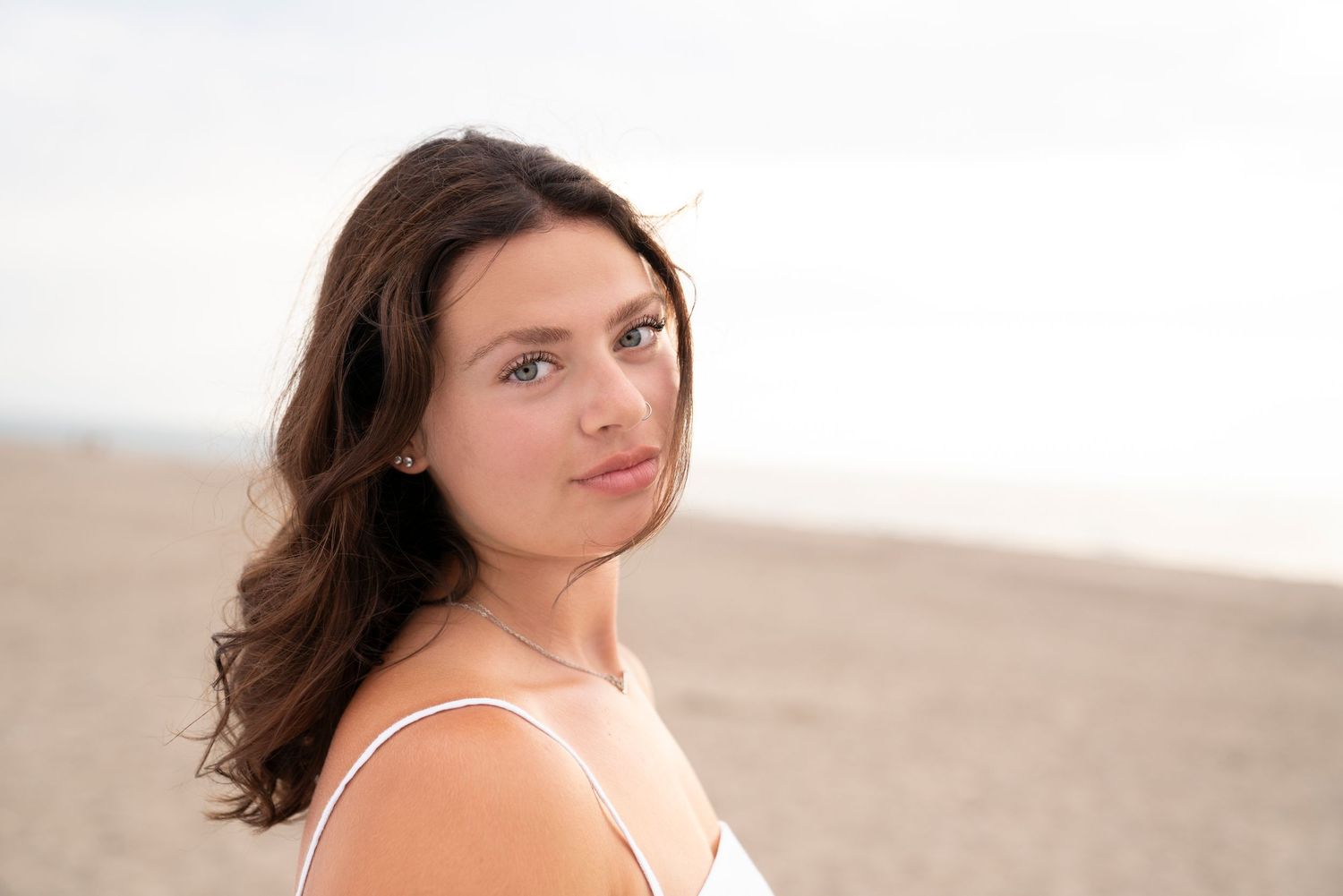 A soft portrait shows someone in a white sundress posing outdoors with natural lighting and shallow depth of field.