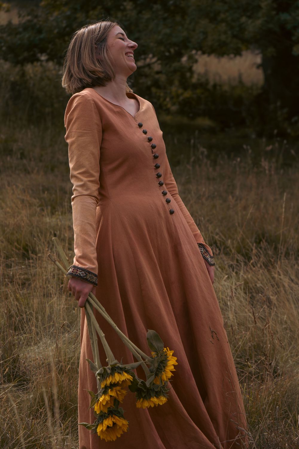 A vintage-style dress with sunflowers against a sunset meadow background. Author novel promotional photoshoot in Gloucestershire.