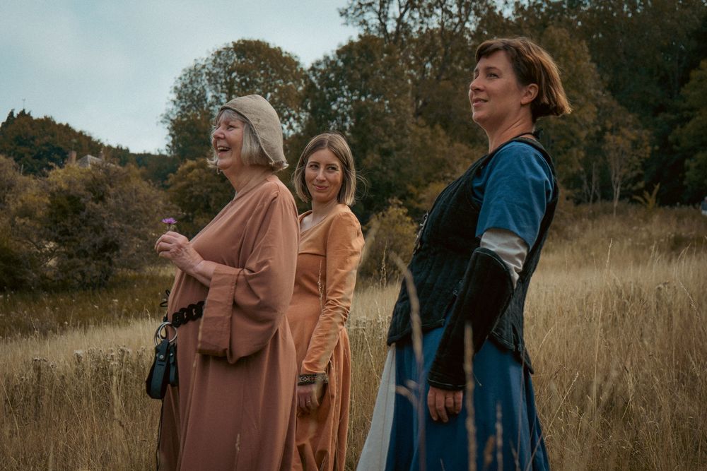 Author novel promotional photoshoot in Gloucestershire. Three people in historical costumes sharing glances in an autumn field long grass