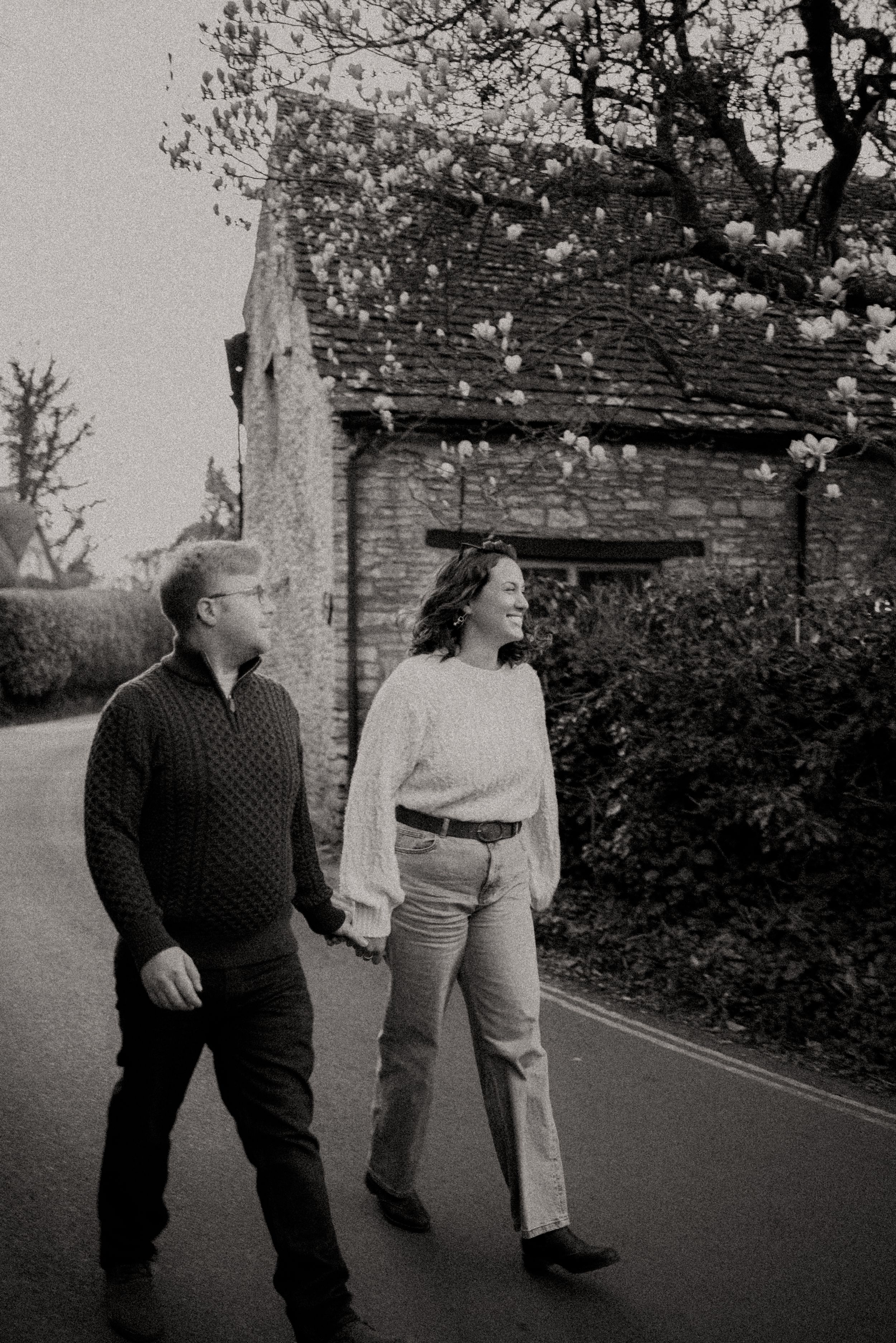 Three black and white photos showing two people walking together on a street near hedges and buildings.