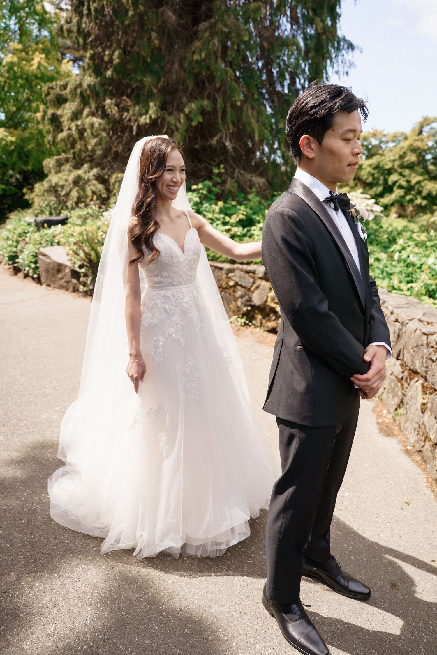 A first look moment between a couple in wedding attire on a garden path.