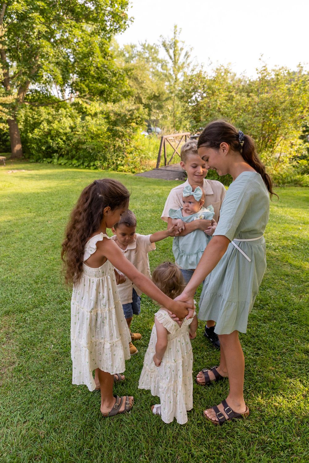 A group of 6 siblings playing ring around the rosie with the second youngest standing in the middle