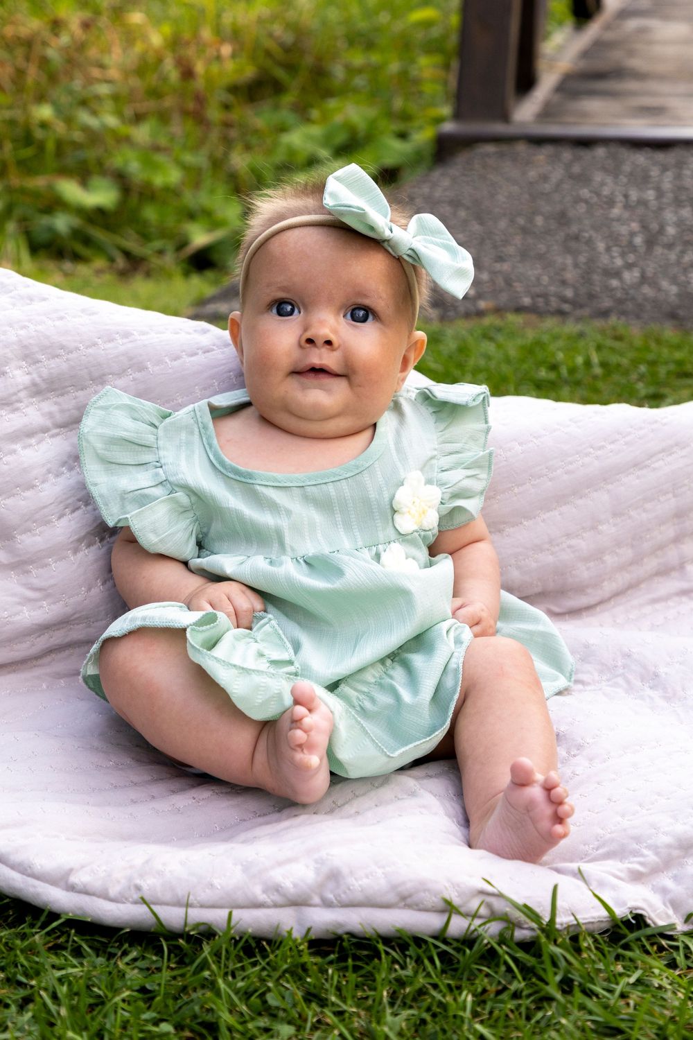 Baby girl propped up with a blanket on the grass