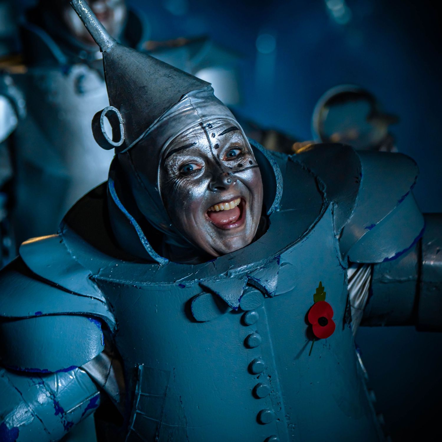 Character in Tin Man costume from Wizard of Oz with theatrical makeup and metallic suit.