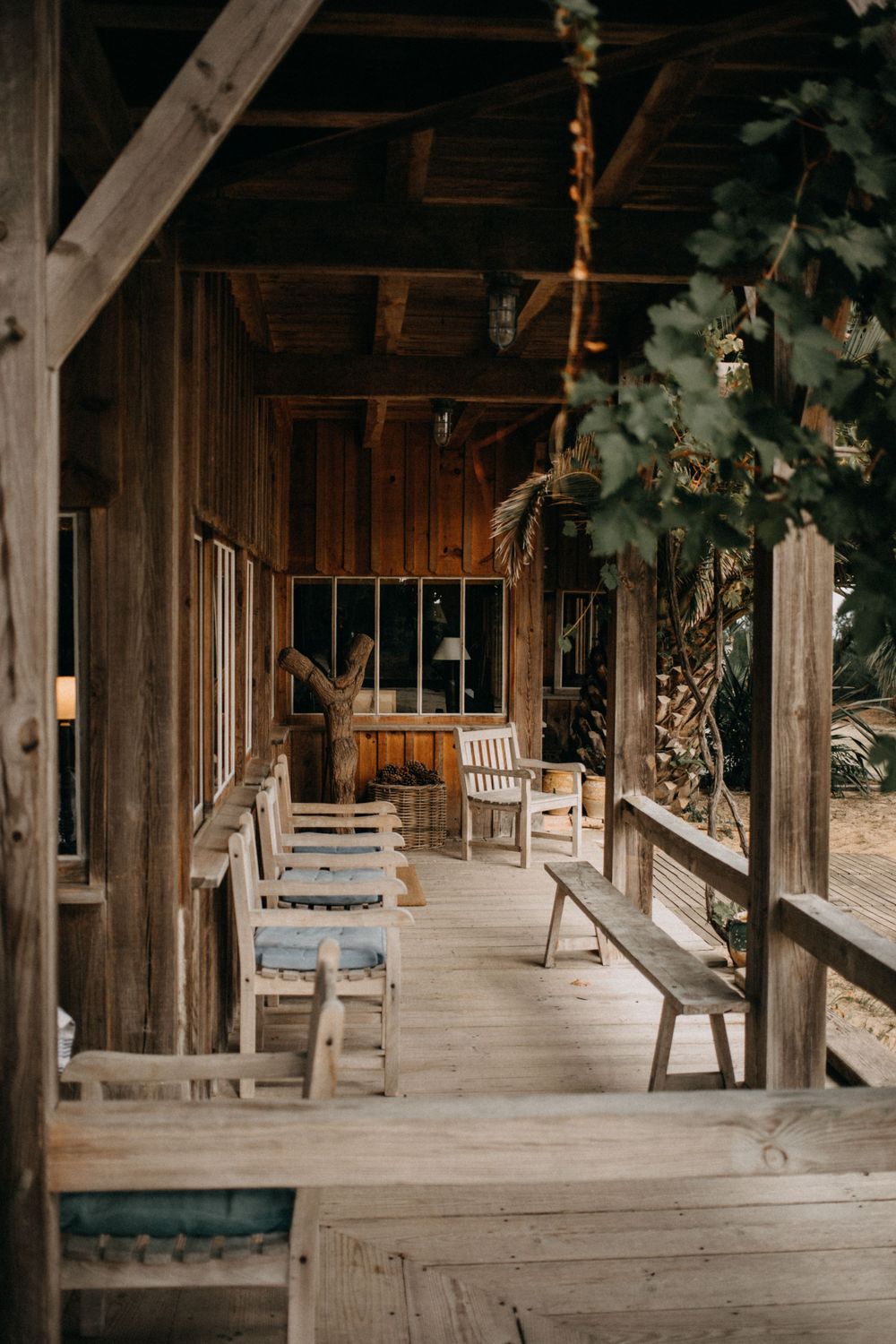 Rustic wooden porch with bench seating and natural wood beams in warm lighting.