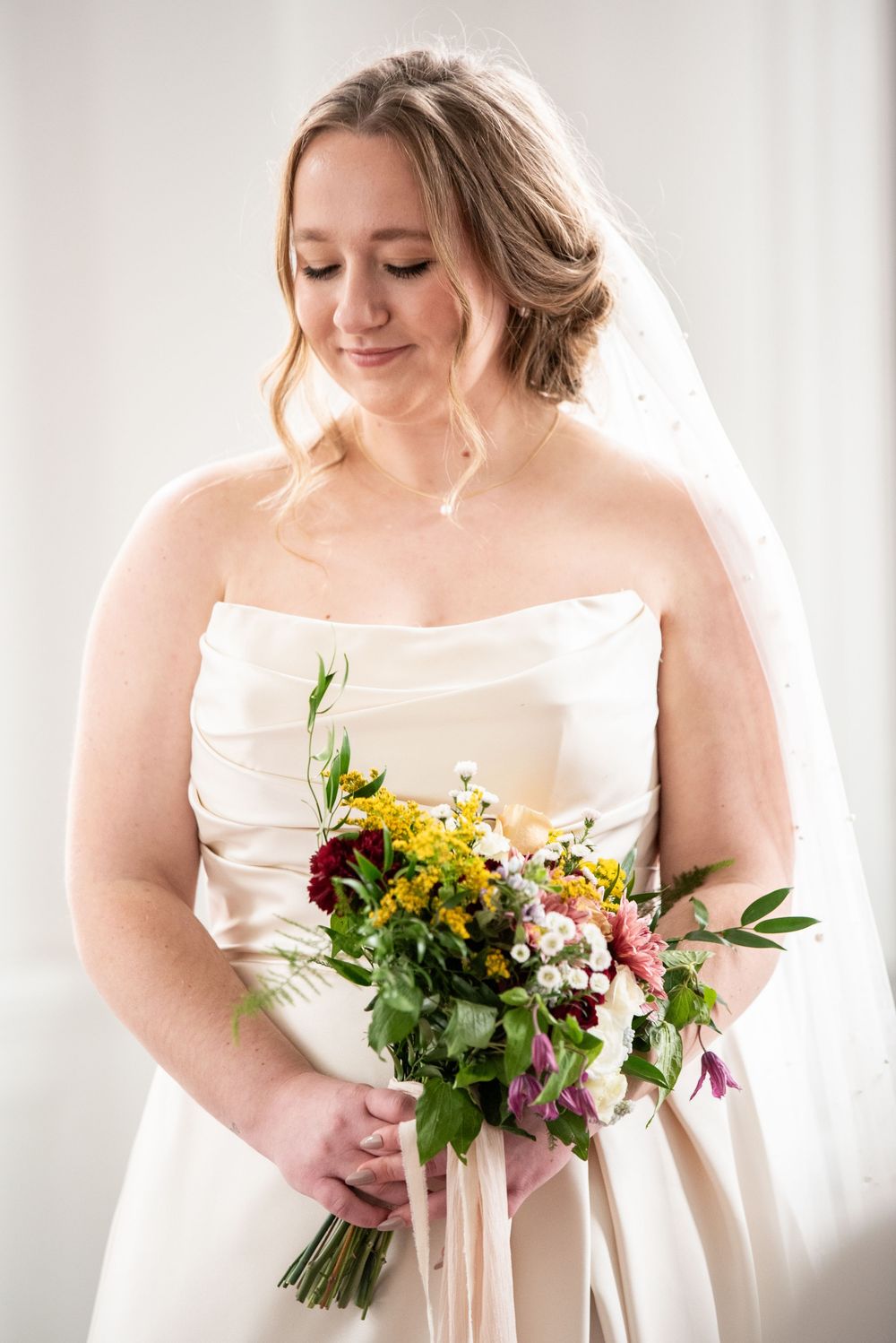 A photo of a bride wearing a white dress, holding a bouquet of flowers on her wedding day.