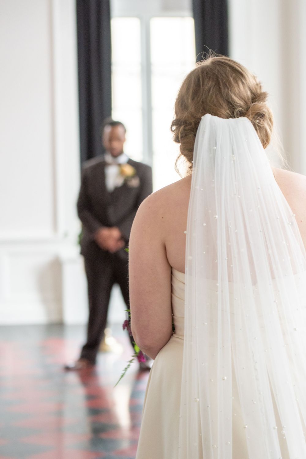 An over-the-shoulder image of a bride looking down the aisle at her soon-to-be husband.