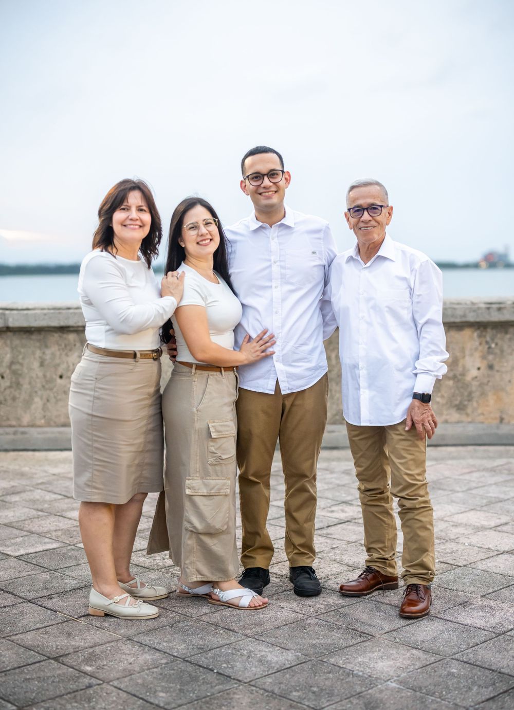 Family of four poses together outdoors in coordinating white and beige outfits.