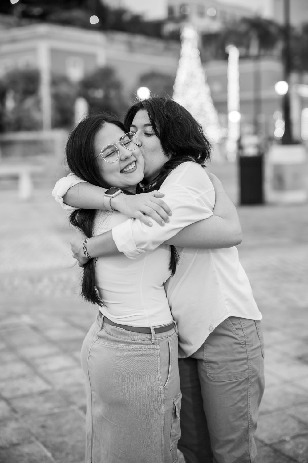 Black and white photo capturing intimate embrace between siblings or friends.