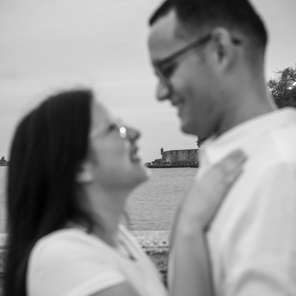 Soft focus black and white portrait of two people gazing at each other by the water.