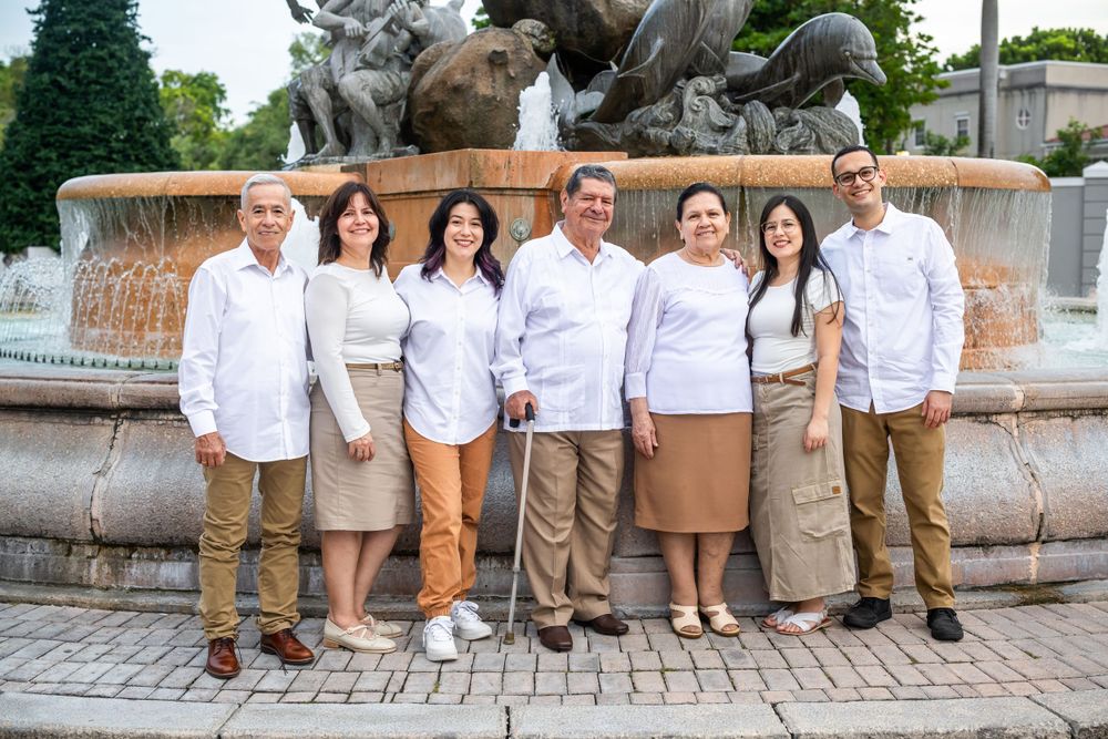 Family group portrait in matching attire posed by ornate fountain.